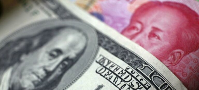 Billete de dólar junto a un billete de yuan
