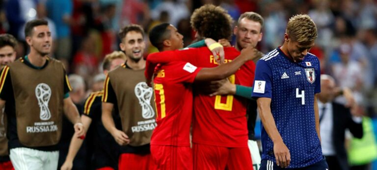 Honda, de Japón, cabizbajo mientras los jugadores belgas celebran la victoria